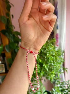 Close-up of a Martisor bracelet with twisted red and white cotton cords and wooden beads, celebrating Romanian tradition