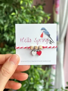 Red and white March bracelet with wooden beads and heart pendants