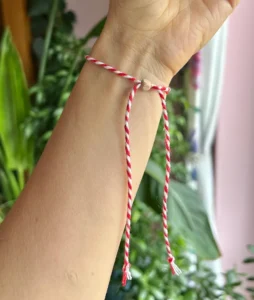 Close-up of the underside of a Martisor bracelet with twisted red and white cotton cords and wooden beads, celebrating Romanian tradition