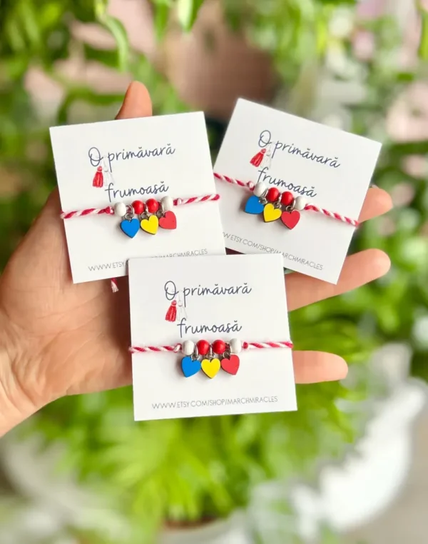 Handcrafted Romanian Martisor bracelet with red and white cotton cords and wooden hearts, symbolizing the arrival of spring.